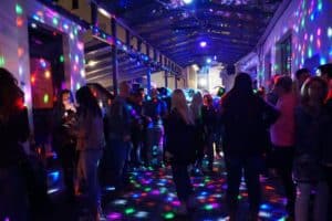 Heller Partykeller mit bunten Lichtern, junge Menschen feiern und tanzen, Atmosphäre voller Spaß und Energie, typische Szene für eine Nachtveranstaltung in einer aktuellen Party-Location.