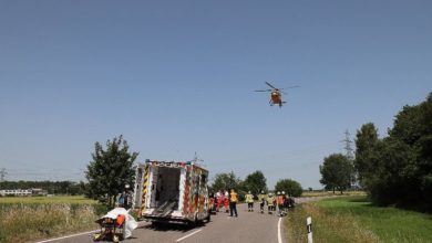 Einsatzkräfte bei einer Rettungs- und Bergungsaktion auf einer Landstraße, Hubschrauber im Einsatz, Einsatzfahrzeug mit Rettungsteam, wichtige Einsatzsituation in der Notfallmedizin, BSAktuell.
